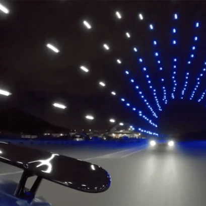 A car drives through a tunnel of drones.